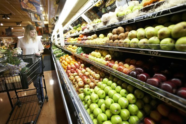 Una mujer está comprando en la sección de productos agrícolas del supermercado.