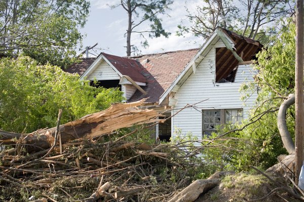 Een beschadigd dak en ramen van een huis nadat een tornado is neergestort.