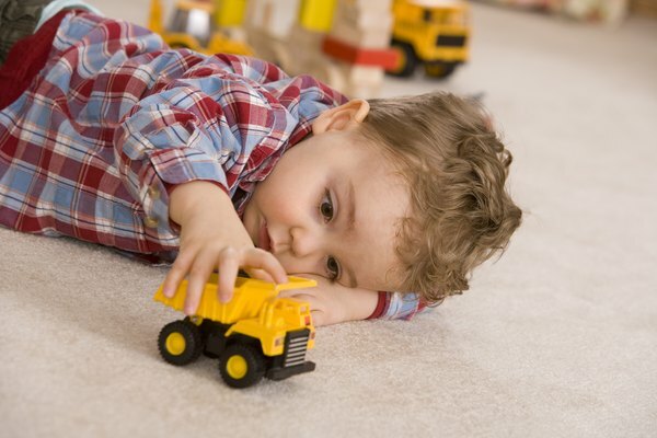 Chłopiec bawi się żółtym autko.